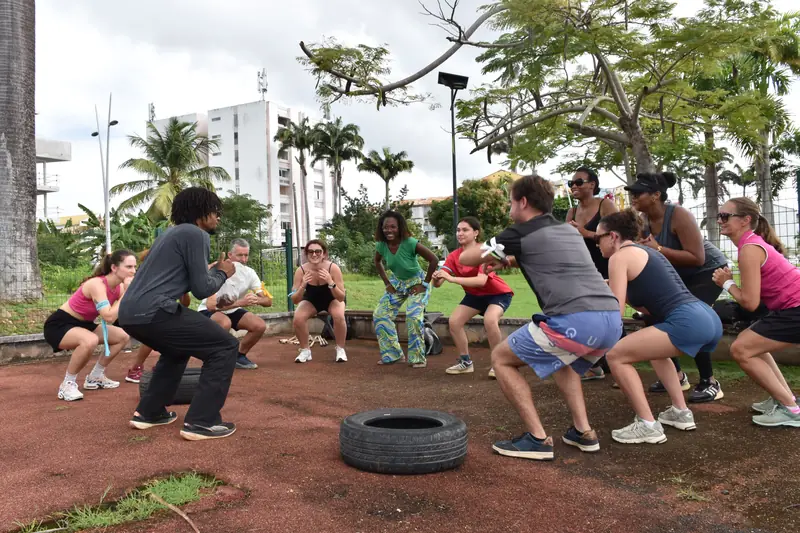Un groupe accroupi en cercle autour d'un pneu pendant l'échauffement, en plein air